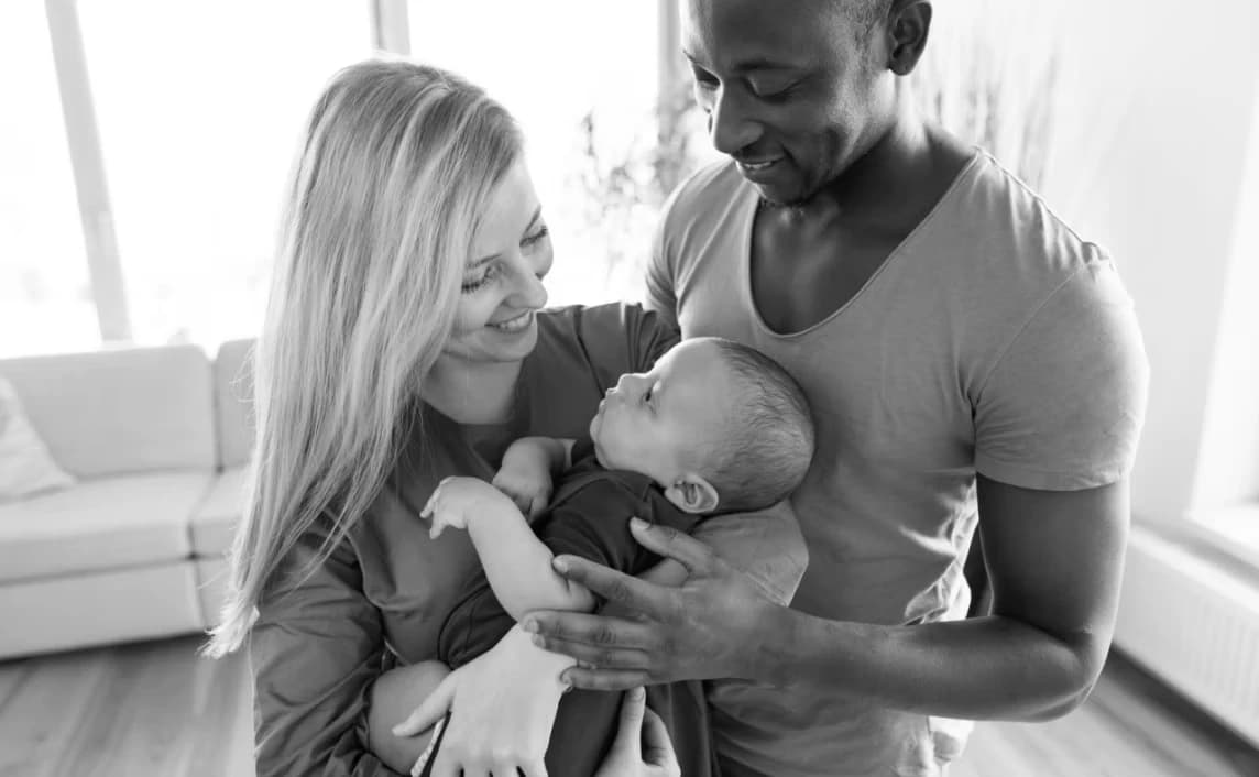 Parents cradle their newborn child at home